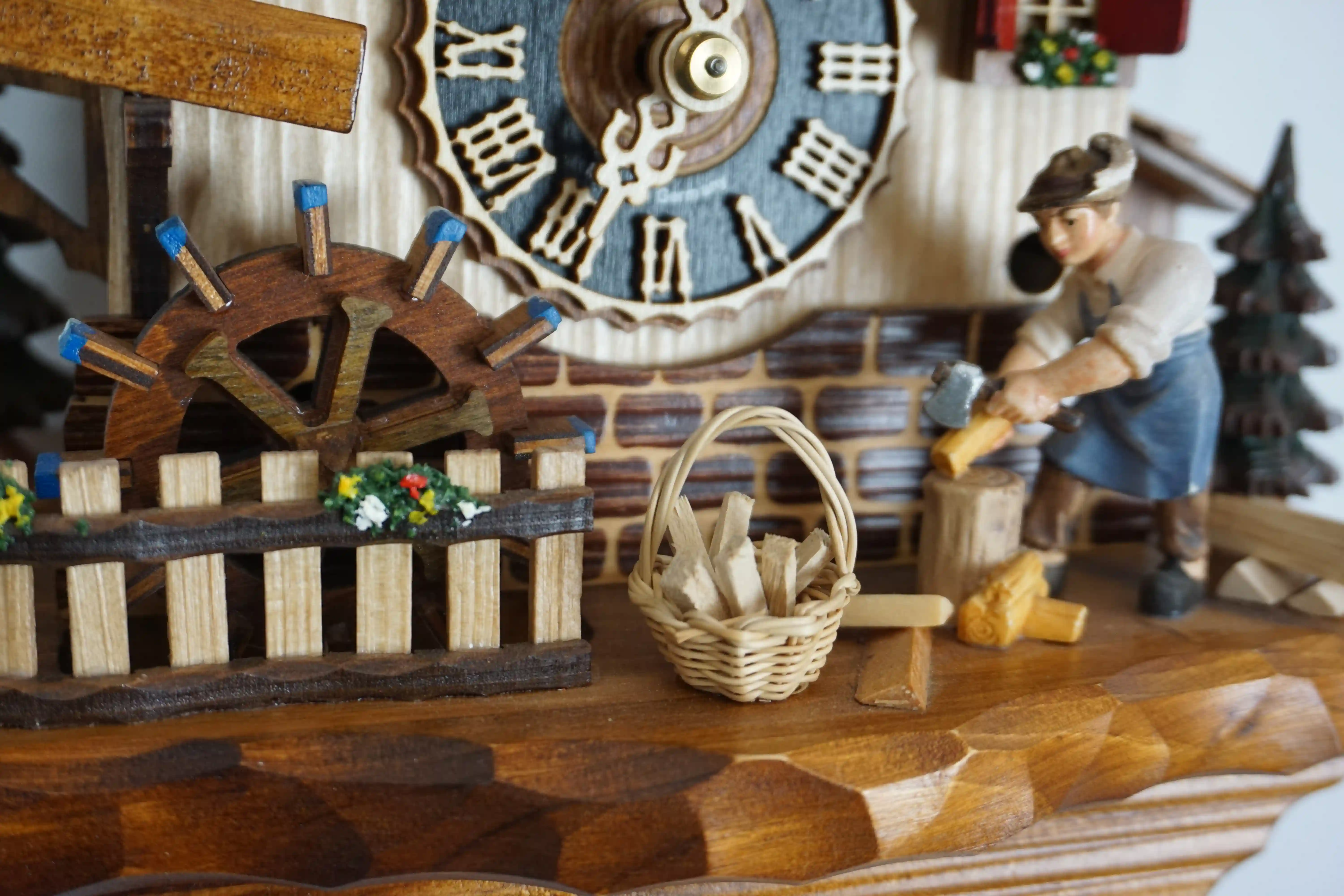 Cuckoo Clock Wood Chopper 1 Day Movement with Music (4) chalet authentic black forest cuckoo clock with a red shingle roof and a wood chopper, as the music plays dancers dance, wood is being chopped and the water wheel turns, the clock is made by Hönes