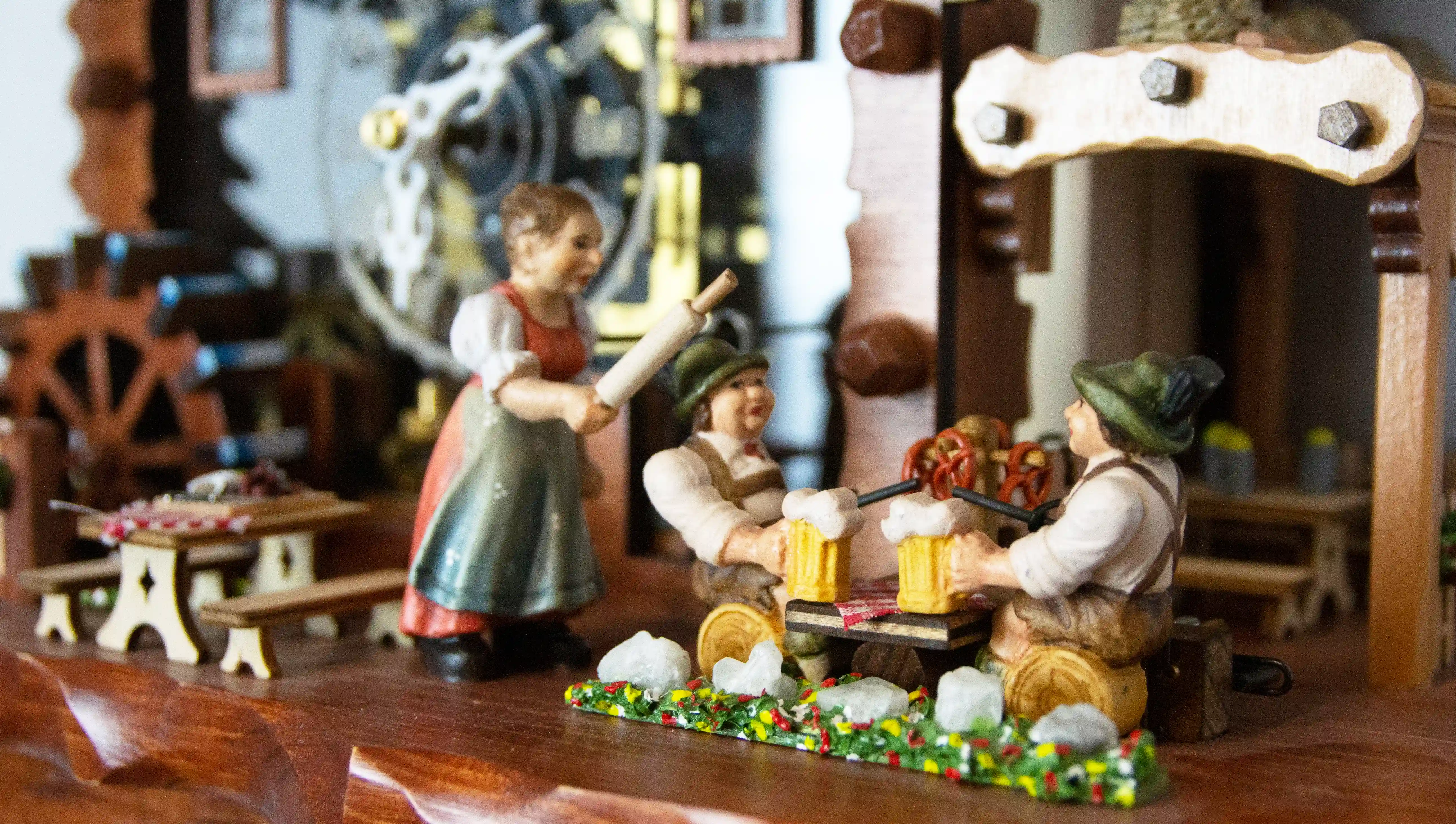 Authentic mechanical large coloful black forest cuckoo clock with transparent plexiglass and visible inside movement. It displays two beer drinkers in the beer garden and the lady with a rolling pin. As the music is playing dancers dance, water wheel turn