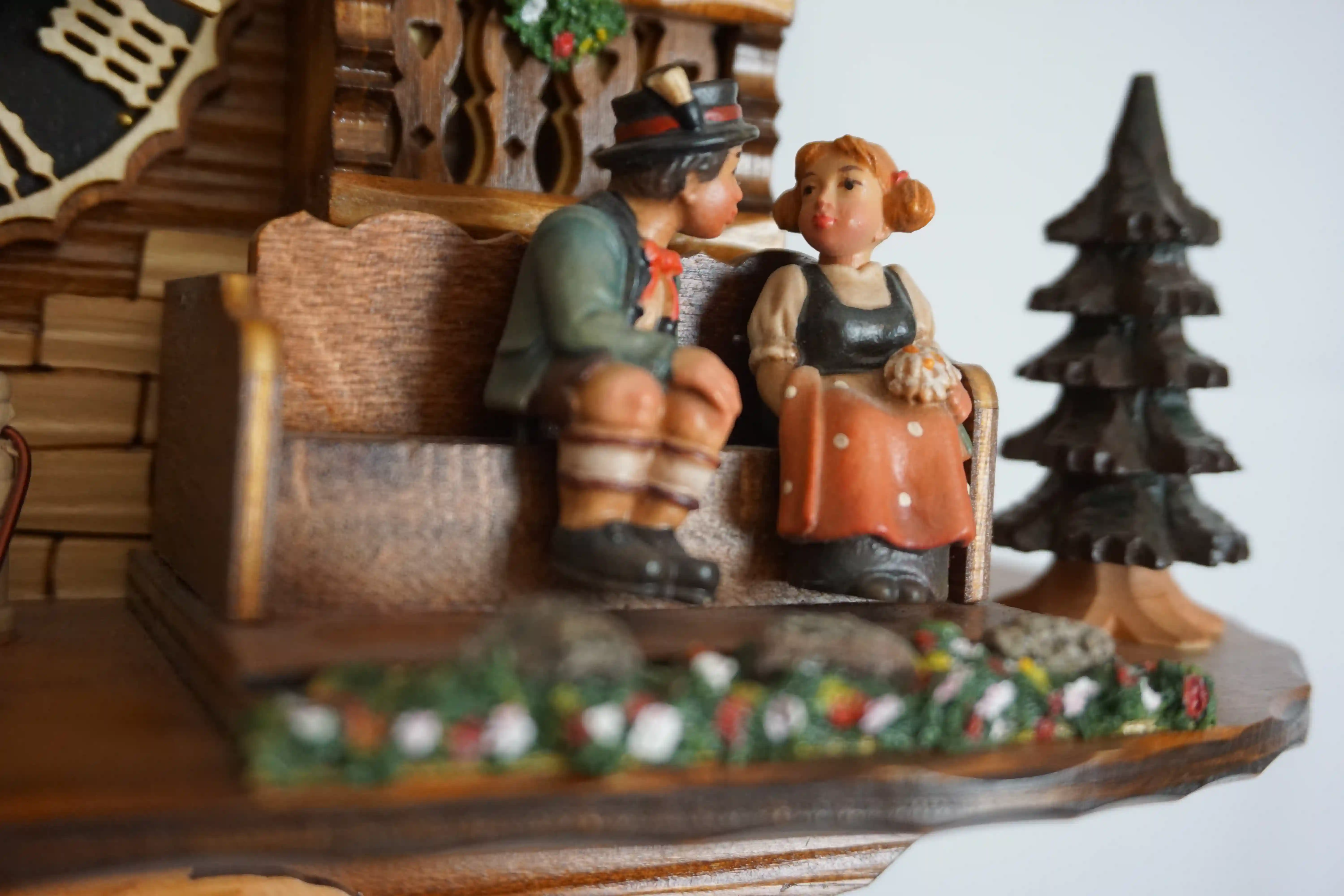 Cuckoo Clock Honeymoon 1 Day Movement with Music (6) Mechanical black forest cuckoo clock decorated to the finest detail, representing a couple on honeymoon sitting on the bench in front of the chalet house sliding thowards each other for a kiss while the music plays, dancers and waterwheel turn